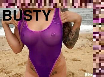Busty bikini babe naughty in her sheer one piece bikini on a public beach