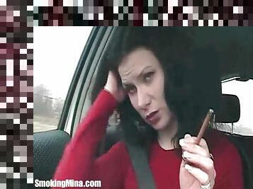 Brunette in the car smokes cigarette lustily