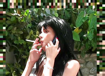 Dark-haired babe is smoking a cigarette